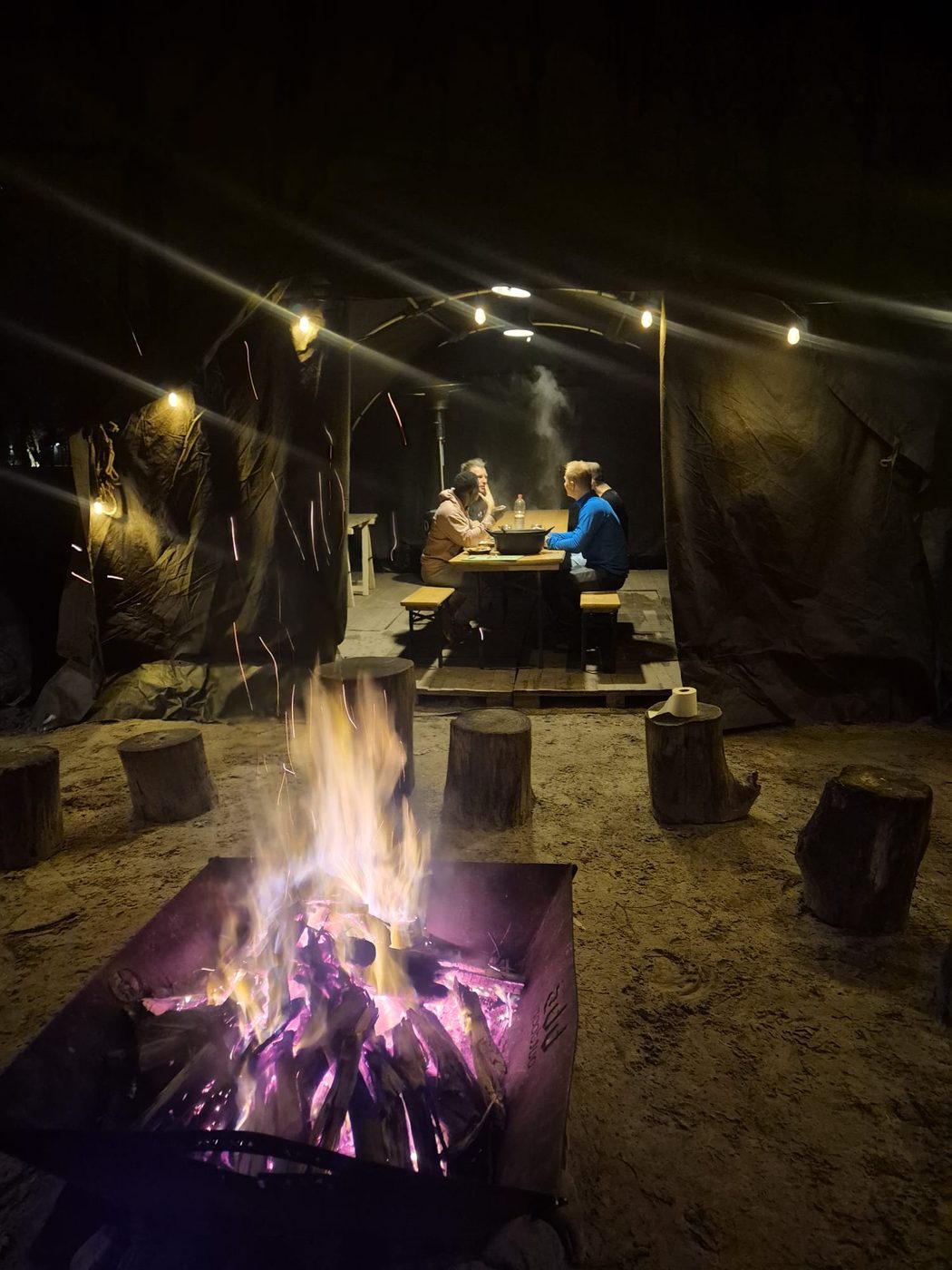 Mannen aan tafel bij het kampvuur in het donker
