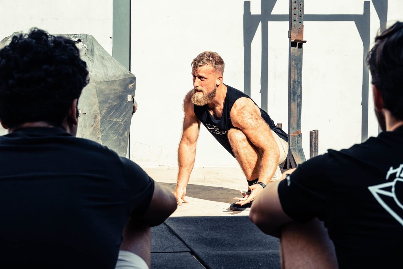 Tim demonstreert een squat aan een groep mannen